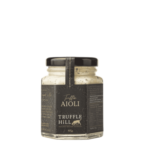 A hexagonal glass jar with a black label branded Truffle Hill. Label describes Truffle Aioli