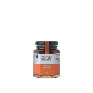 A hexagonal glass jar with a black label branded Truffle Hill. Label describes Truffle Honey